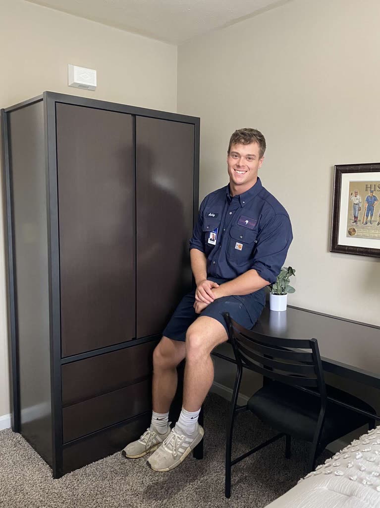 Ashby in a maintenance uniform at an apartment desk
